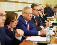 Na zdjęciu rząd osób - radnych województwa podlaskiego - przy stole do obrad. Głos zabiera pierwszy z lewej marszałek województwa Artur Kosicki
