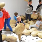 Dzieci na wystawie bawią się poduszkami w kształcie i kolorze ziemniaków