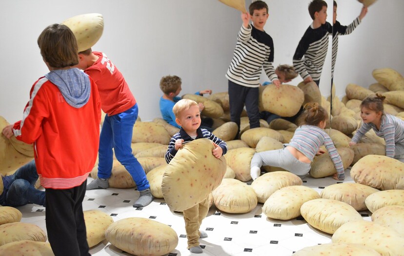 Dzieci bawiące się poduszkami w kształcie i kolorze ziemniaków na wystawie w Zachęcie
