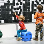Dzieci na wystawie bawią się biało-czarną tablicą z klockami
