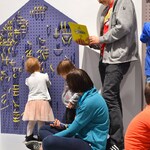 Dzieci na wystawie bawią się fioletowo-żółtą tablicą sensoryczną
