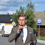Robert Jabłoński przy mikrofonie na tle drogi.