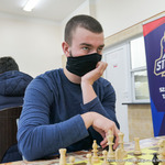 Młody szachista patrzy do przodu a w tle baner UKS Stoczek 45