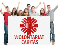 Grupa osób stojących za tablicą ze znakiem graficznym Caritas i napisem Wolontariat Caritas