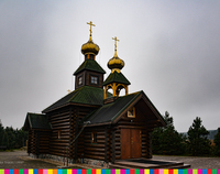 Drewniana cerkiew z dwiema wieżami uwieńczonymi złotymi kopułami z krzyżem prawosławnym.