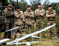 Grupa żołnierzy stoi obok samolotu bezzałogowego.