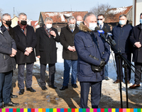 Grupa mężczyzna w maskach. Na pierwszym planie wicemarszałek Marek Olbryś mówi do mikrofonu