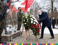 Marszałek Artur Kosicki składa wieniec z biało-czerwoną wstęgą przed pomnikiem. W tle flagi oraz żołnierz stojący na warcie