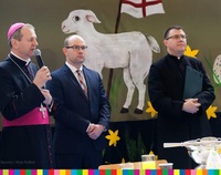Na zdjęciu widoczny od lewej abp Tadeusz Wojda, marszałek Artur Kosicki oraz kapłan. W tle widoczny rysunek baranka.