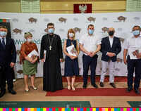 Pięć osób stojących na tle ścianki z logo Województwa Podlaskiego