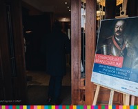 Mężczyzna stoi tyłem w otwartych drzwiach, po prawej stronie plakat konferencji naukowej - „Jan Klemens Branicki – splendor i miraż”