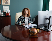 Prof. Marta Kosior - Kazberuk siedzi za biurkiem z ogromnym monitorem