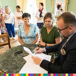 Wicemarszałek Łukaszewicz podpisuje dokument w towarzystwie kobiet z Koła Gospodyń Wiejskich