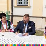 Wicemarszałek Łukaszewicz podpisuje dokument w towarzystwie kobiet z Koła Gospodyń Wiejskich