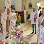 Biskup stoi przed wieńcem dożynkowym w kształcie figury Matki Bożej, w ręku trzyma kropidło.  