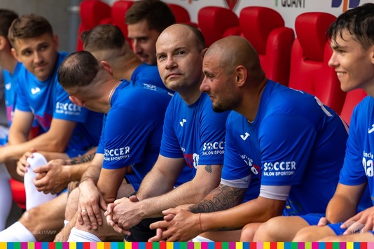 Artur Kosicki, kapitan drużyny piłkarkiej siedzi na ławce z resztą zespołu