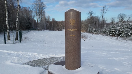 Pomnik -trójstyk granic w Bolciach w zimowej scenerii. Na drugim planie drzewa pokryte śniegiem