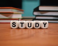zdjęcie przedstawia biurko, w tle książki, na pierwszym planie kostki ułożone w napis "study"