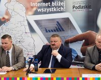 przy stole w sali konferencyjnej siedzą (od lewej): dyrektor z NASK, wicemarszałek i dyrektor z urzędu marszałkowskiego. Na pierwszym planie mikrofony redakcji radia i tv