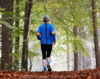 starszy człowiek w stroju sportowym biegnie po leśnej ścieżce