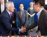 Minister wita się podając dłoń z prezesem firmy Samsung, w tle pani Ambasador Korei