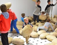 Dzieci bawiące się poduszkami w kształcie i kolorze ziemniaków na wystawie w Zachęcie