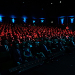 Publiczność siedząca w półmroku na widowni opery