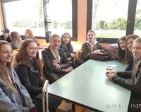 Grupa uśmiechniętych uczniów siedząca przy stole