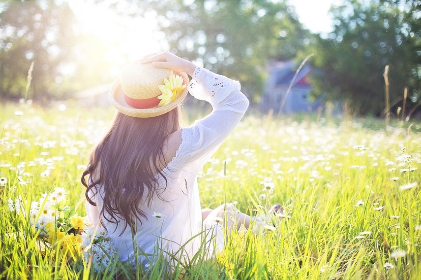 Kobieta w kapeluszu na słonecznej łące latem