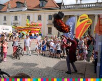 Mężczyzna robi pokaz wybuchu. Na placu przez Pałacem Branickich stoi kilkadziesiąt osób, w tym dzieci.