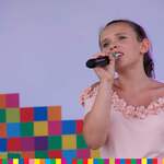 Młoda dziewczyna śpiewa do mikrofonu na scenie