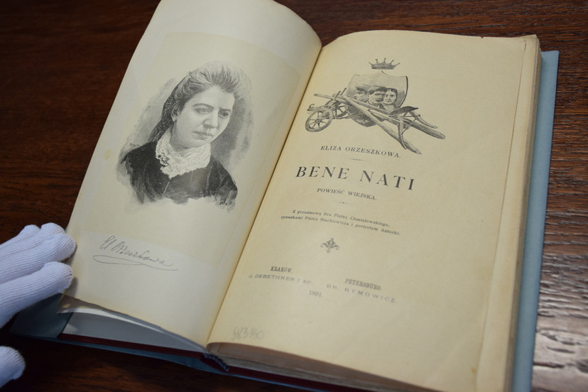 Książka autorstwa E. Orzeszkowej pt.: "Bene Nati" z 1891  -rozłożona na stole: na lewej stronie portret autorki, po prawej - strona tytułowa.