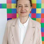 Prof. Iżykowska-Lipińska stoi na tle banneru z logo podlaskiego - kolorowe piksele żubra.