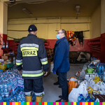 Marszałek Artur Kosicki oraz strażak stojący w garażu z dużą ilością wody i jedzenia.