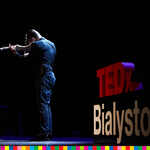 Skrzypek grający na skrzypcach na tle logo TEDx