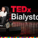 Przemawiająca kobieta na wózku inwalidzkim z logiem TEDx za plecami