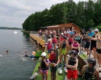 Grupa dzieci i młodzieży na brzegu jeziora.