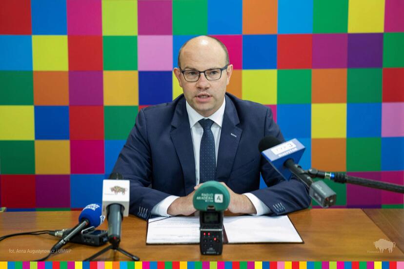 Marszałek Artur Kosicki na konferencji powyborczej na tle kolorowych kwadratów