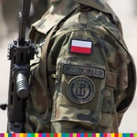 Ramię żołnierza trzymającego broń z naszytą na bark flagą Polski