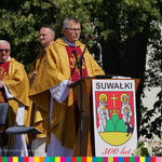 Ksiądz przemawia z ambony z herbem miasta Suwałki