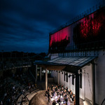 Gmach Opery i Filharmonii Podlaskiej podświetlony na czerwowo, widok na amfiteatr podczas koncertu