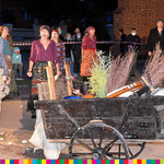 Drewniany wóz wypełniony wiadrami i miotłami, wokół śpiewające aktorki