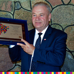 Wicemarszałek Marek Olbryś prezentuje w podniesionych dłoniach pamiątkowy grawerton