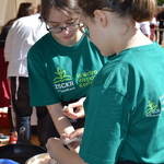 Dwie dziewczyny w zielonych koszulkach wrzucają jedzenie do garnka