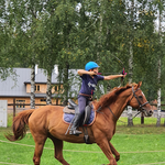 Chłopiec siedzi na koniu i strzela z łuku