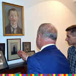 Dwóch mężczyzn ogląda portrety wiszące na ścianie.