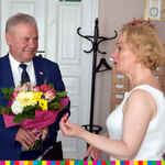 Mężczyzna z wiązanką kwiatów rozmawia z kobietą.