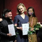 Dwoje nagrodzonych uczestników trzyma róże i dyplomy na scenie.