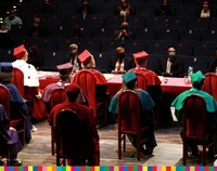 Osoby siedzące tyłem w togach podczas inauguracji roku akademickiego.