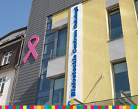 Budynek Białostockiego Centrum Onkologii z wyeksponowaną różową wstążką na jego fasadzie.